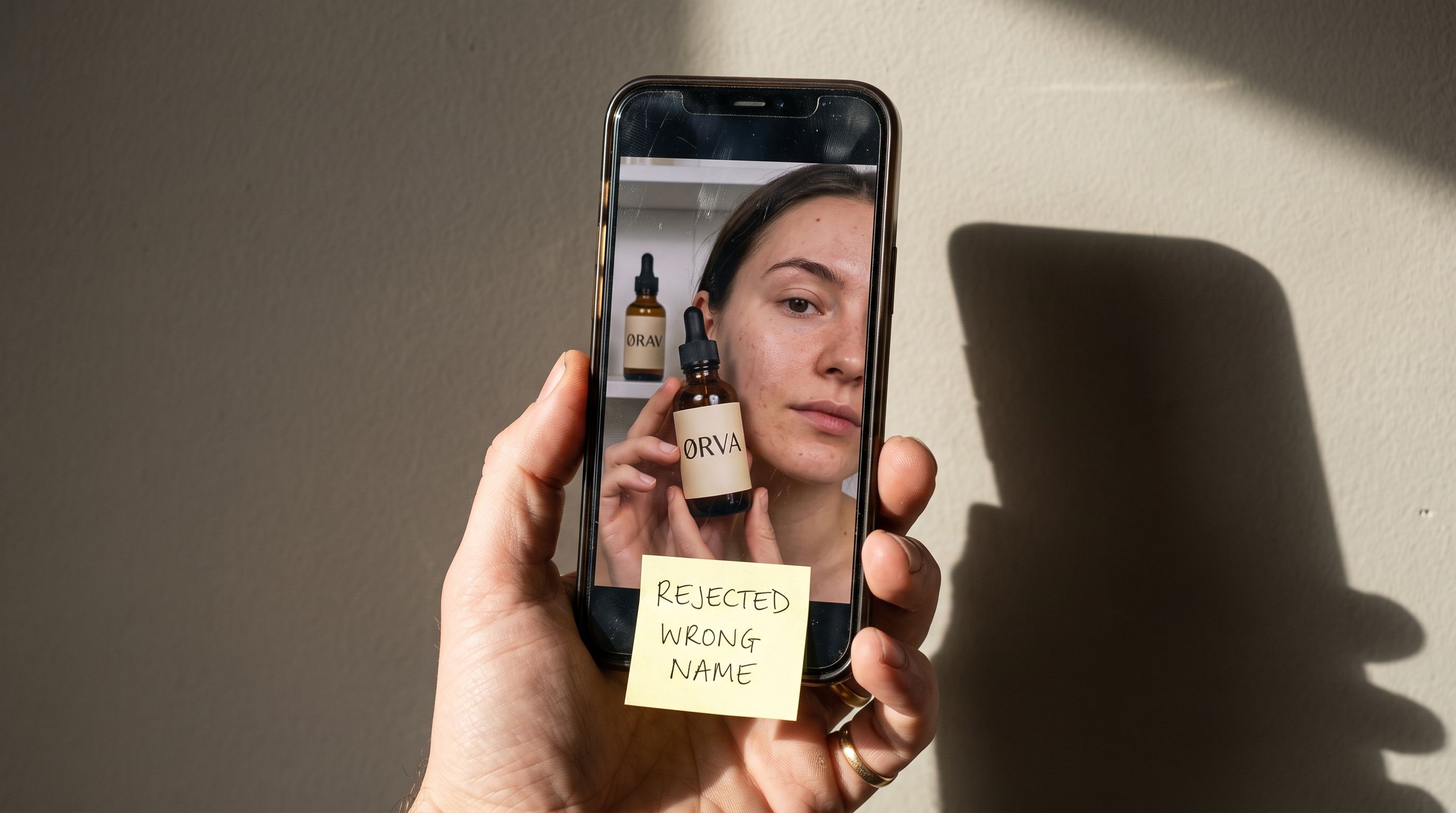 Hand die een telefoon vasthoudt met een sticky note met de tekst Afgewezen Verkeerde Naam