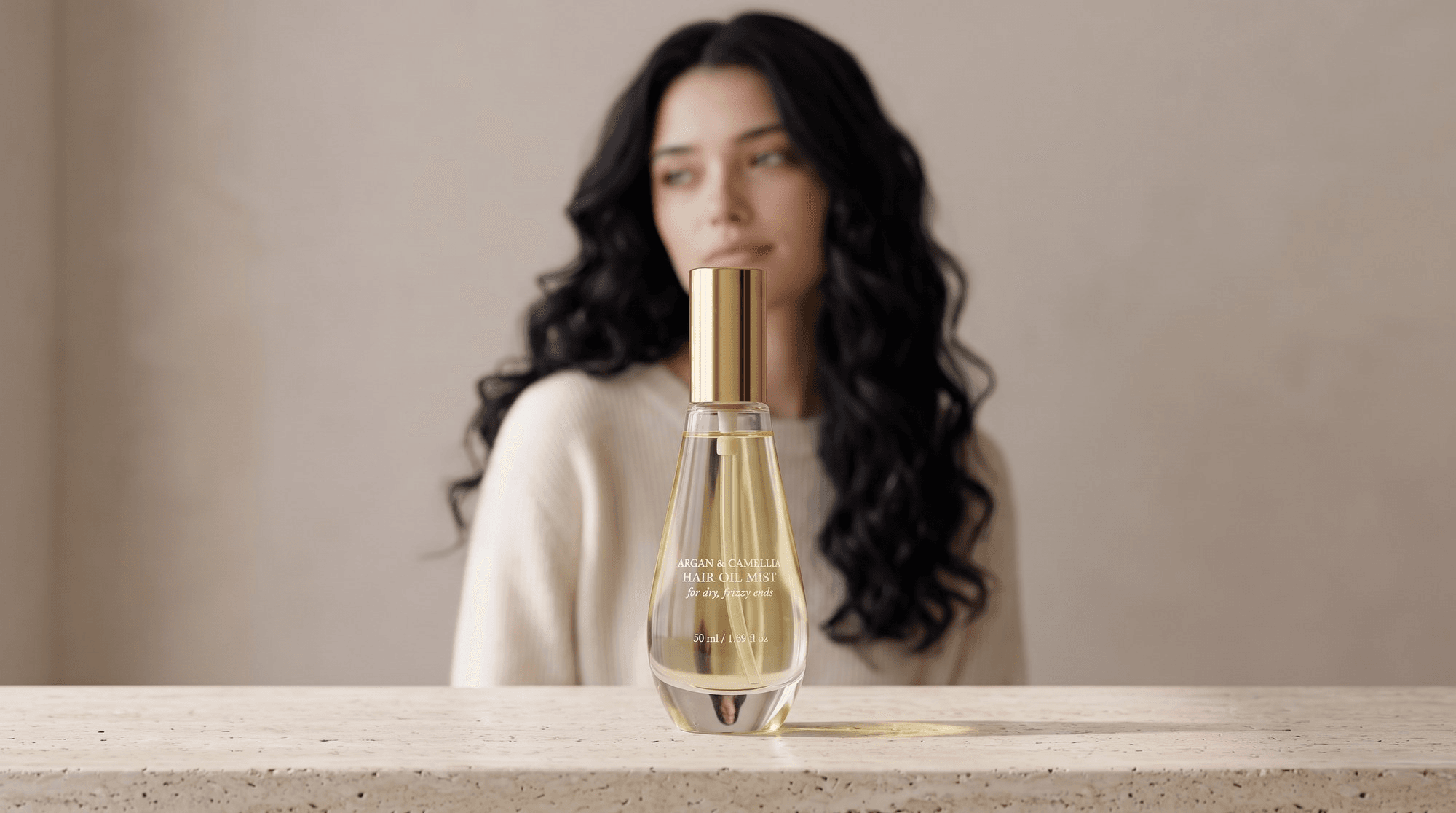 Amazon A+ hero banner example: a teardrop-shaped glass hair oil mist bottle with a gold spray cap in sharp focus on a travertine ledge, with a dark-haired model in a cream knit sweater looking off to the side in soft light behind it