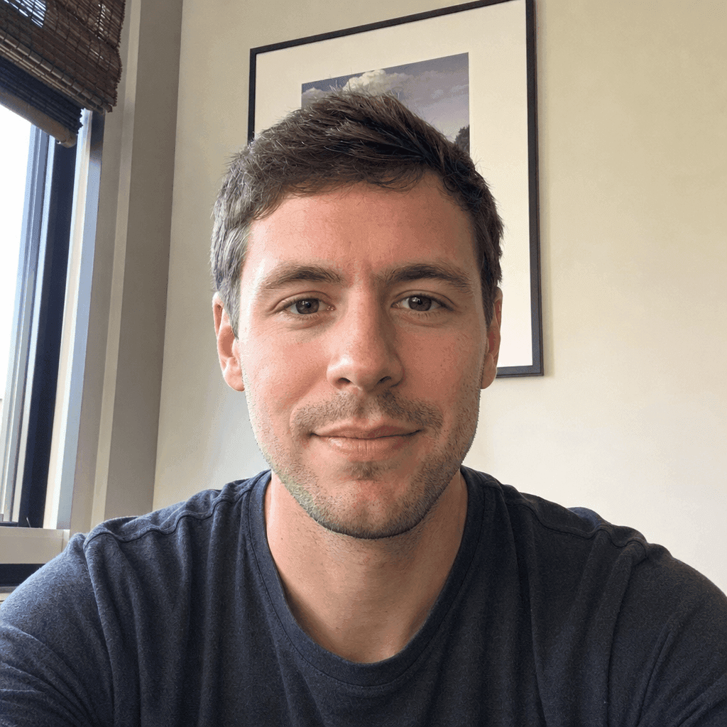 Smiling man with short brown hair wearing a dark grey t-shirt