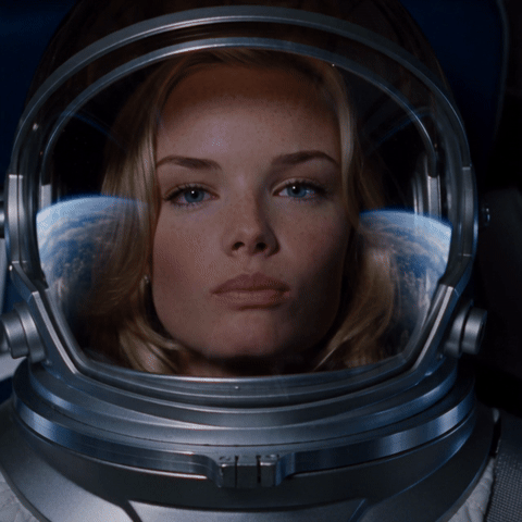 GIF made with ChatGPT and Seedance 2.5 from one portrait: a blonde woman in a silver space suit blows a pink gum bubble inside her helmet, it bursts onto the center of her visor, and she goes cross-eyed before grinning