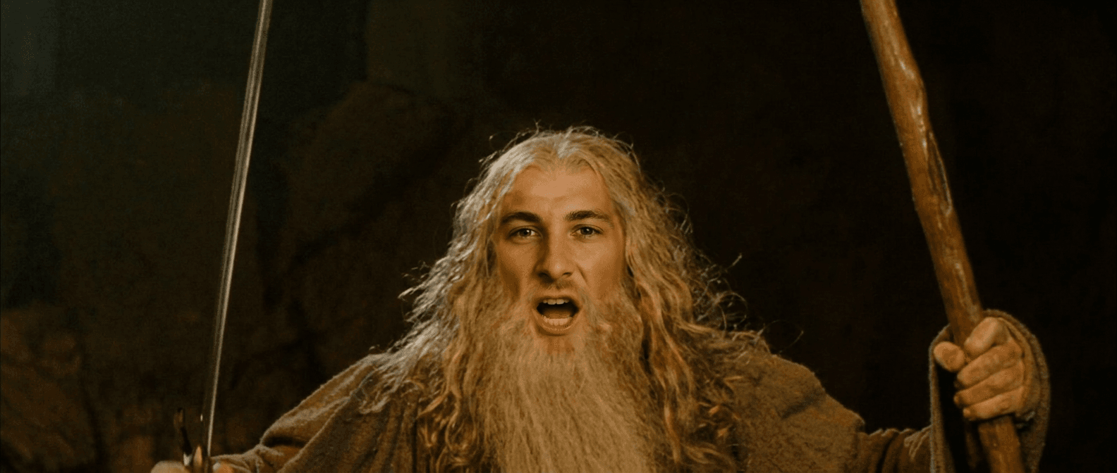 A bearded man shouting while holding a sword and a staff