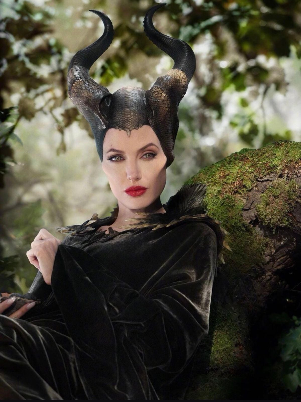 Angelina Jolie as Maleficent with large black horns in a forest