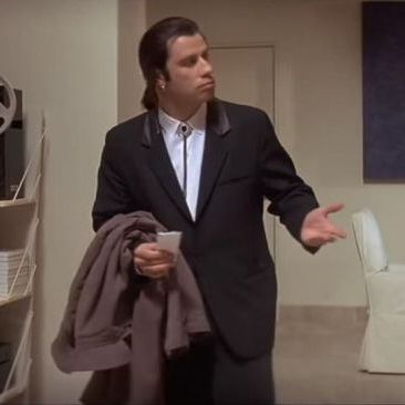 Confused John Travolta in a suit looking around and gesturing