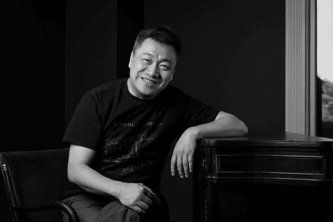 Smiling man leaning on a desk in a black and white photo