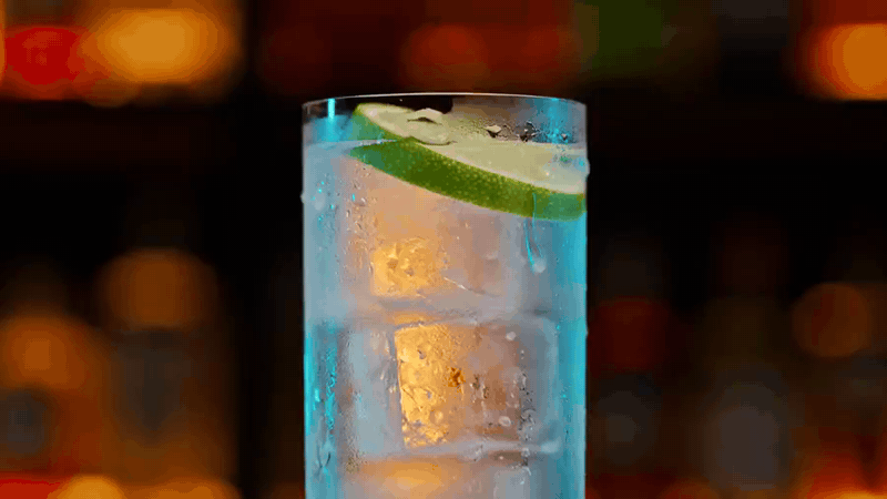 Tall glass filled with ice cubes and a lime slice