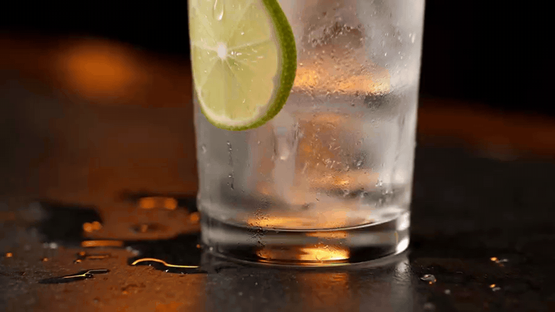 A sweating glass of iced water with a lime slice
