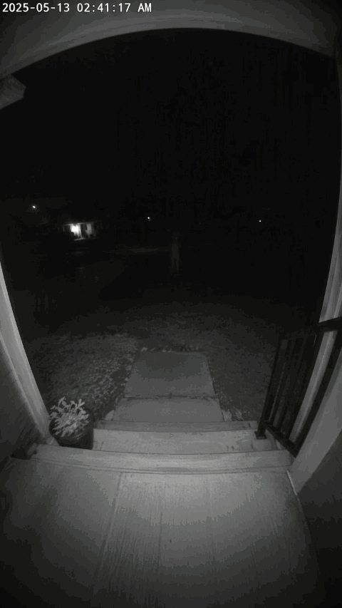 Doorbell camera footage capturing a dark front porch and lawn as a hooded figure with glowing eyes manifests at the base of the steps and dissolves into empty space