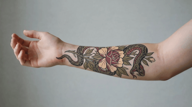 Forearm tattoo of a snake coiled around a large peony flower