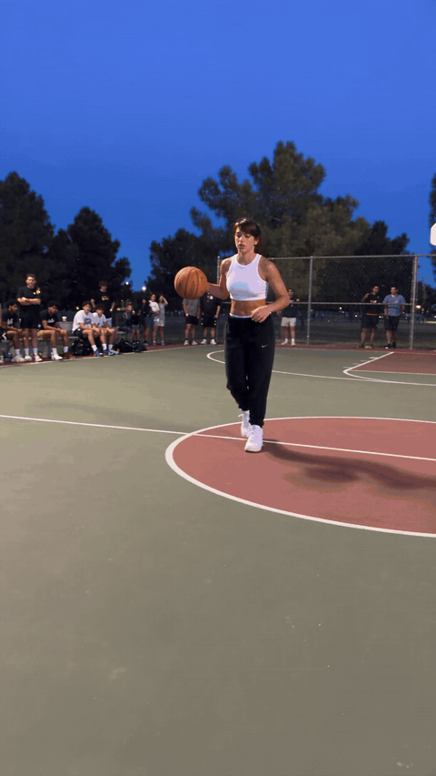 AI dunking video made with Seedance 2.5 from one portrait photo, a woman with a high ponytail crosses over a defender, slams the ball through a