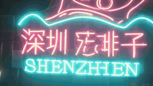 Pink and cyan neon sign displaying Chinese characters and SHENZHEN