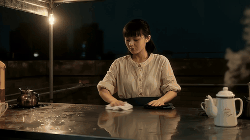 Woman wiping down a metal counter outdoors at night