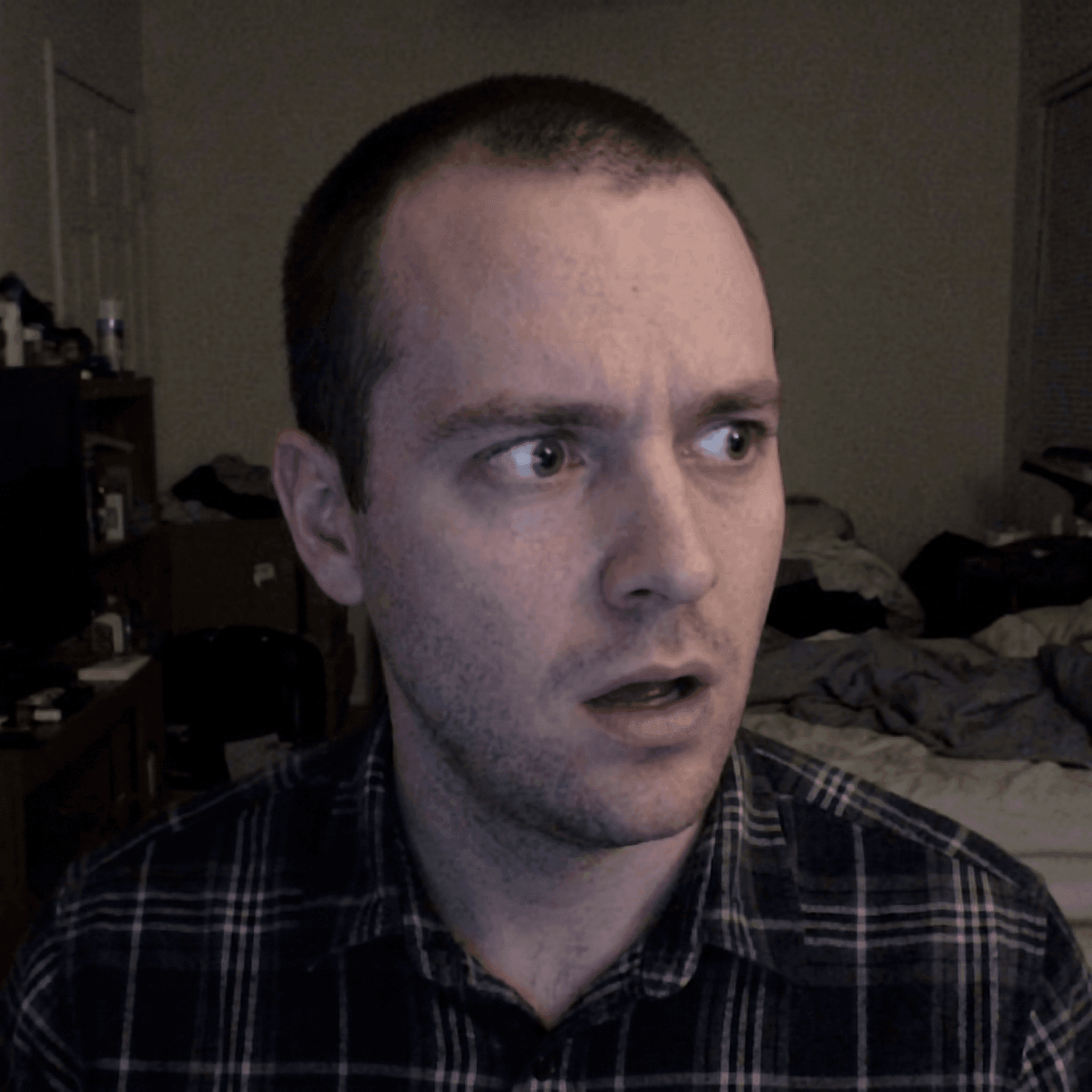 Startled man in a plaid shirt looking sideways with open mouth